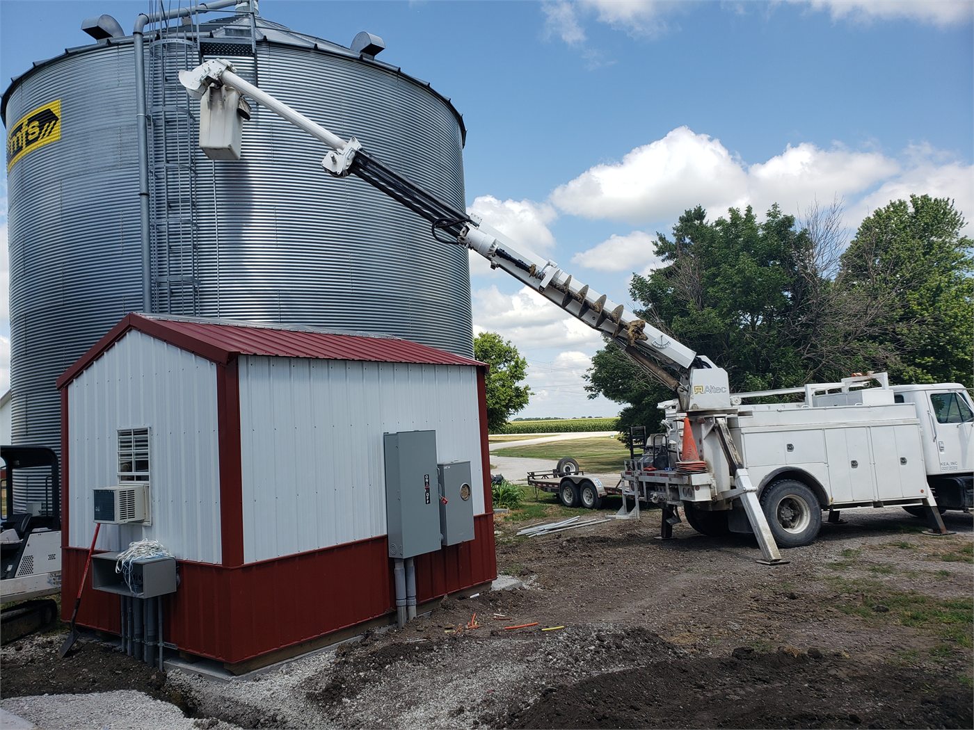Bucket truck working beside a grain bin and service building